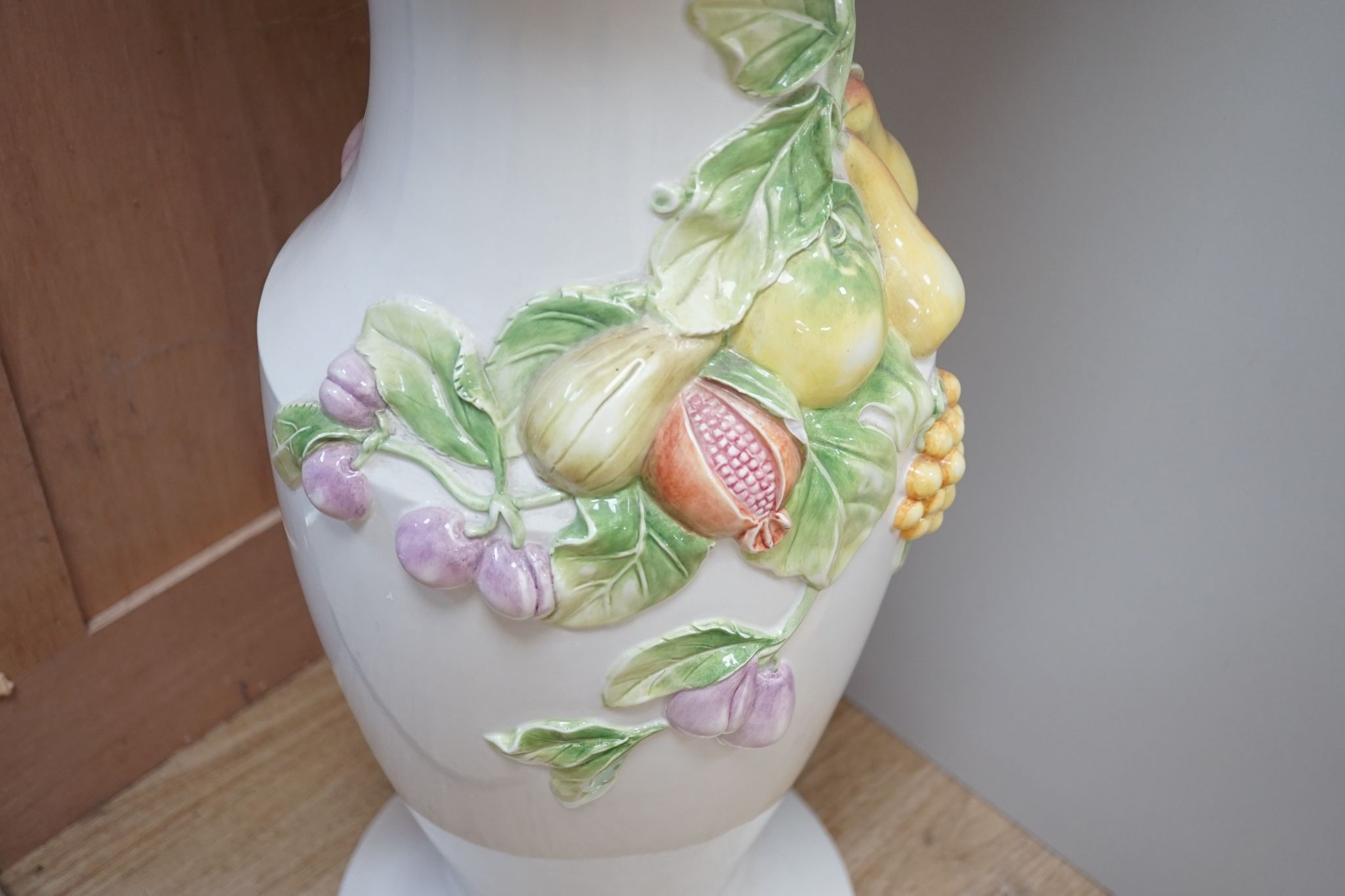 A modern Italian pottery jardiniere and stand, with floral and fruit decoration, 104 cms high.